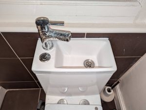 Wash basin is built into toilet. Dirty hand water is emptied directly into the toilet cistern, saving water.