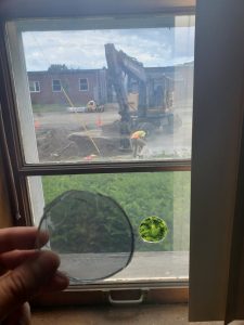 circle of glass knocked out of window by chip of concrete thrown from circular saw cutting kerbstone outside