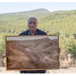 Man position with picture of forest he restored.