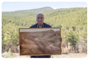 Man position with picture of forest he restored.